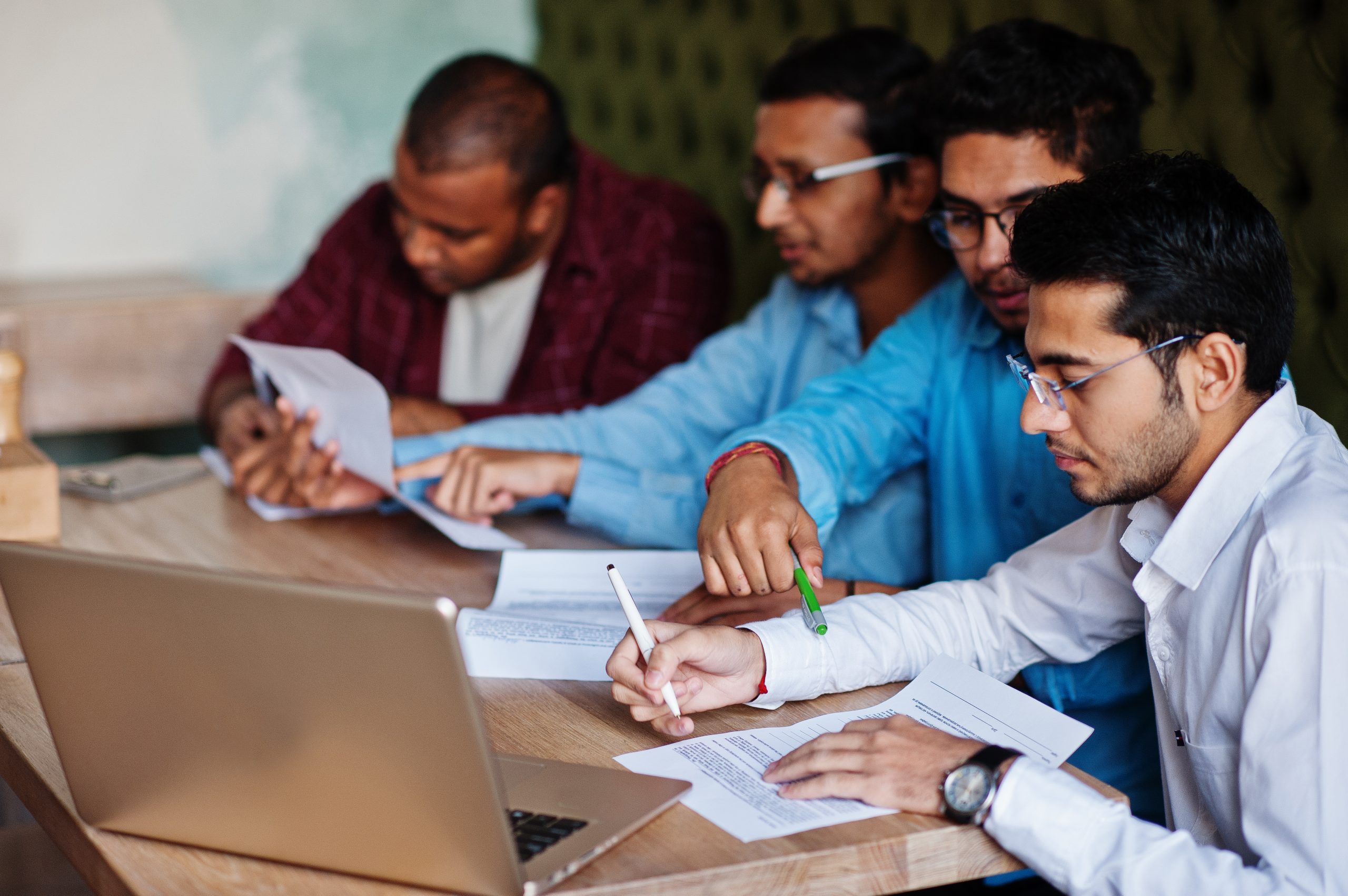 A group of diverse Indian students in business attire discussing a project in a modern university classroom, representing an MBA program.